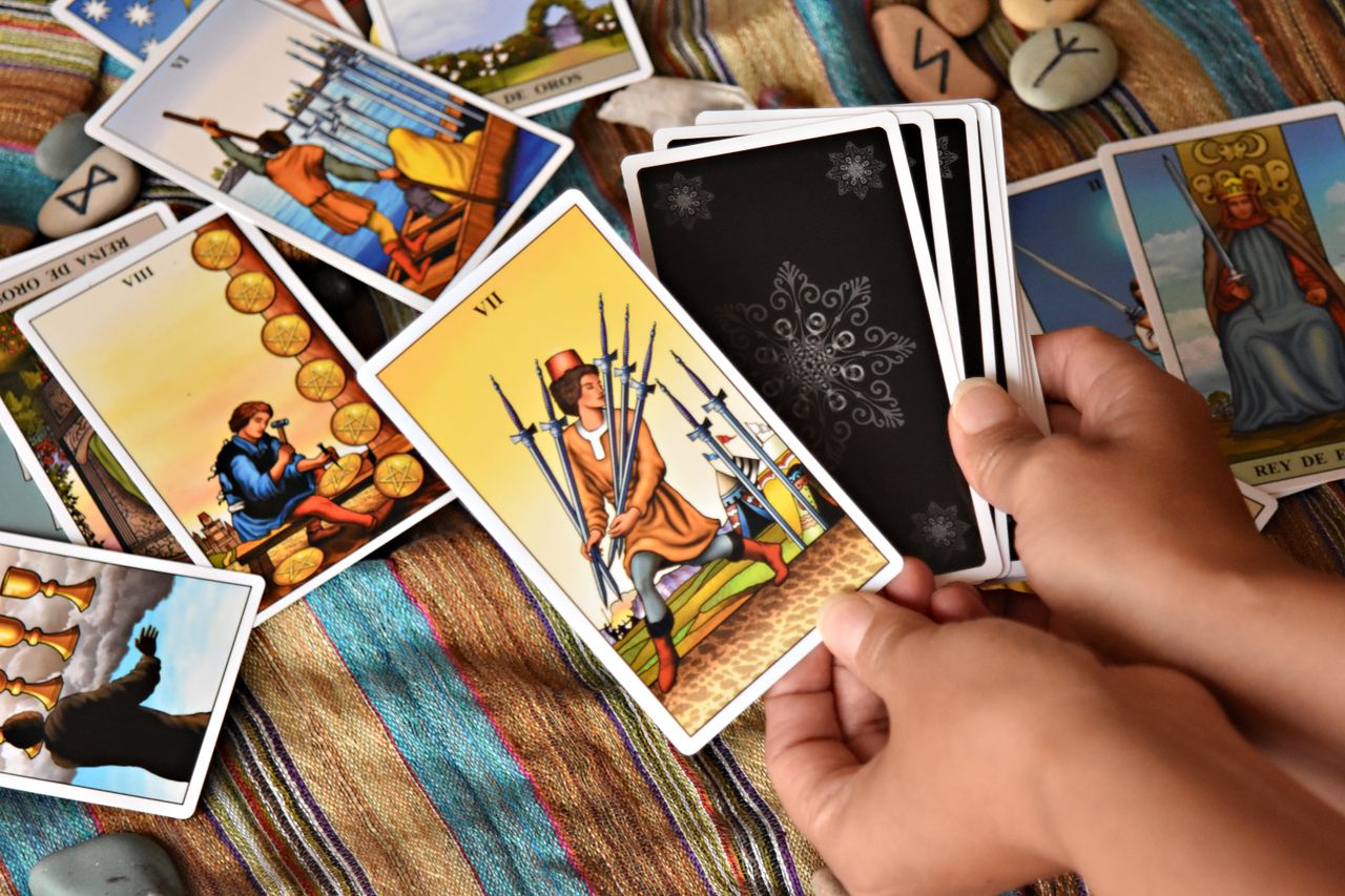Close-up of hands holding Tarot cards on a colorful cloth, ready for divination.
